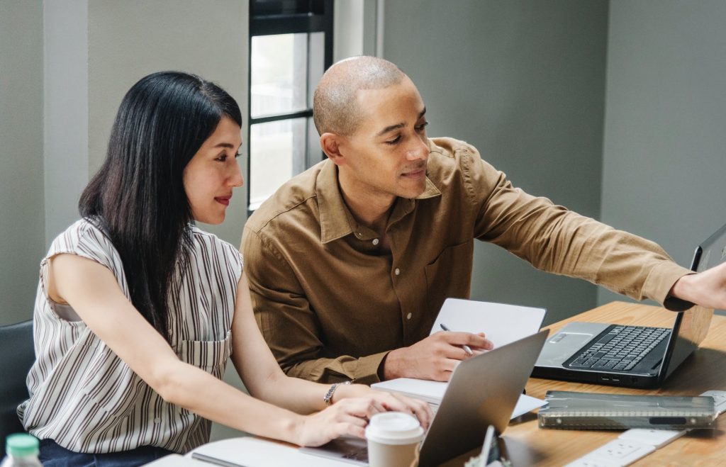 focussed man showing a woman something on his computer