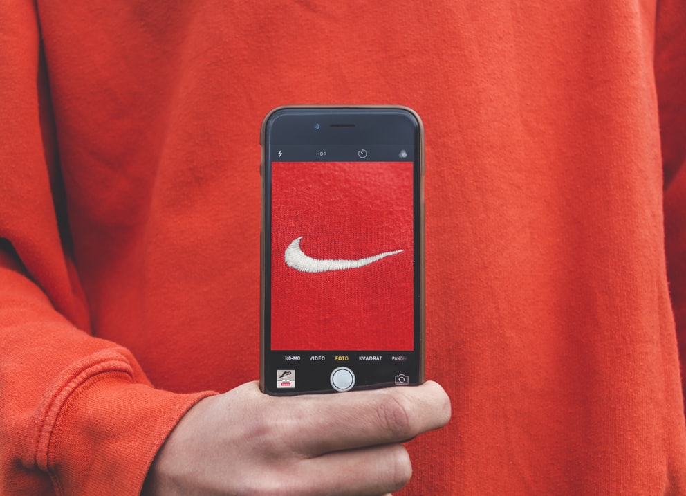 Nike logo with a smart phone help up in front of it